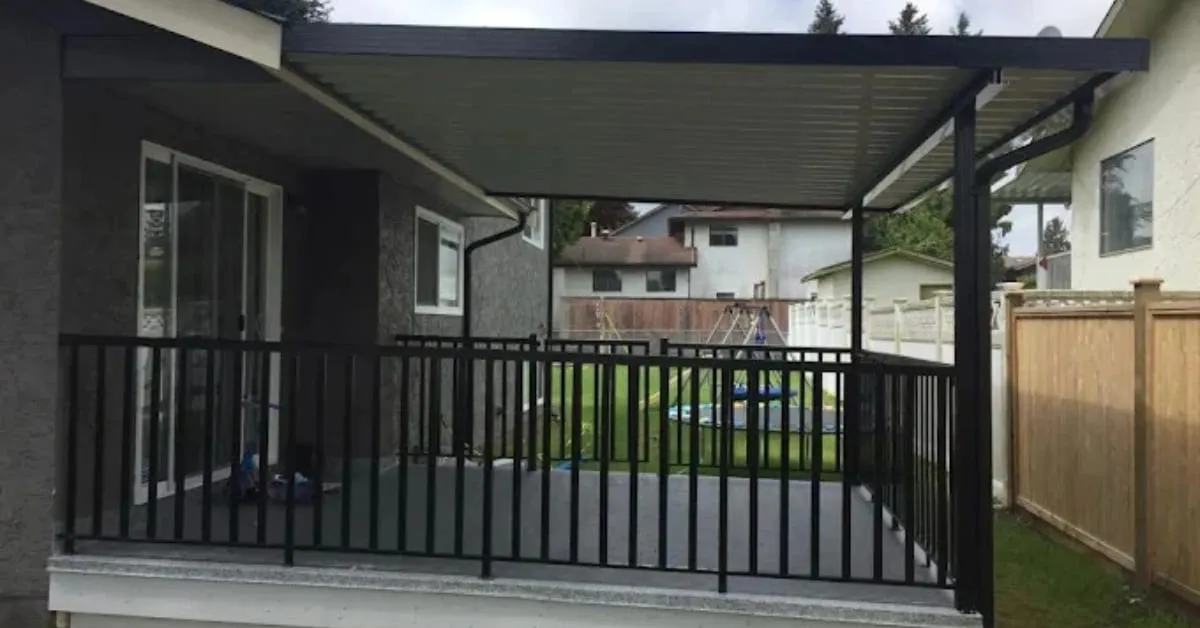 Covered back deck with black aluminum railings overlooking a fenced backyard