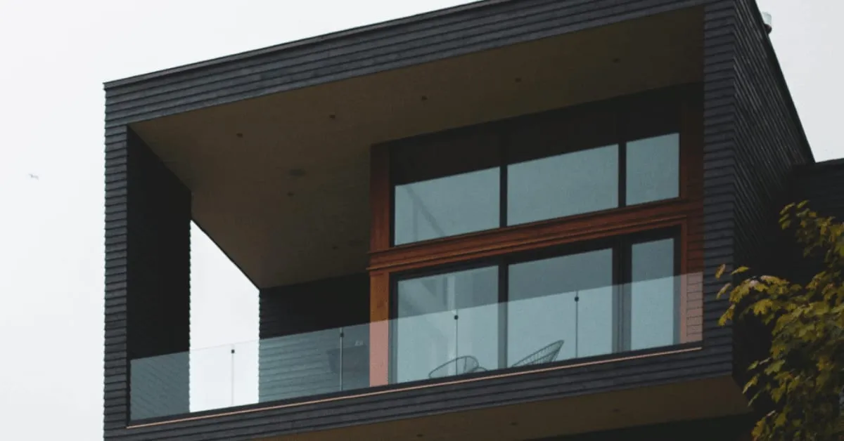 Modern dark-sided house with a frameless glass balcony railing