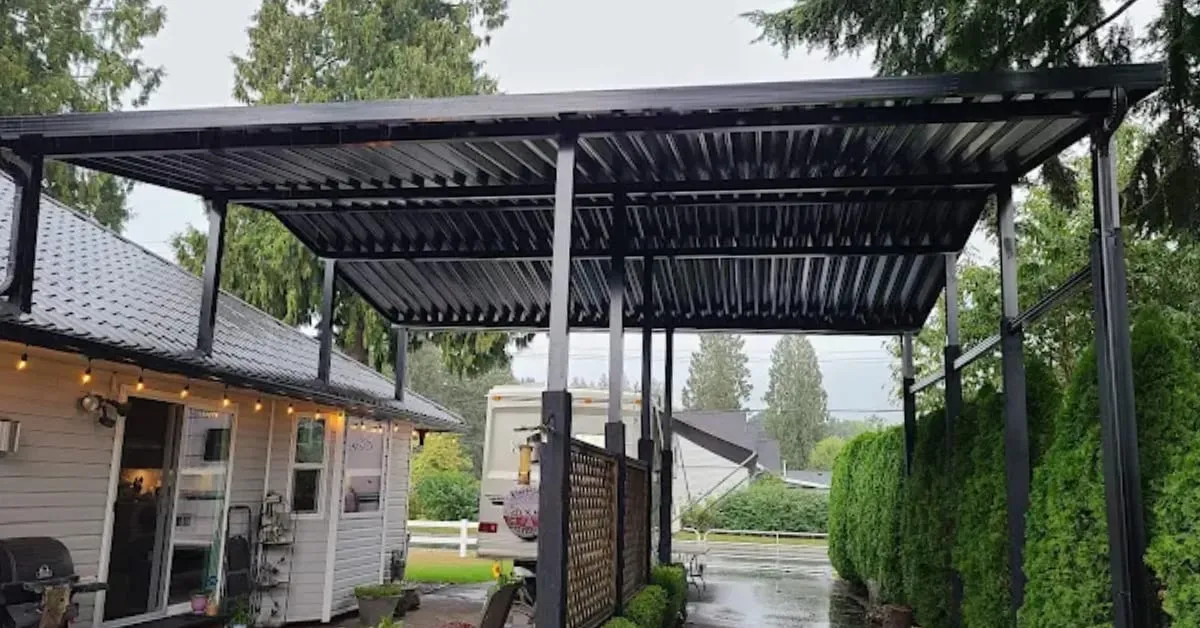 Black louvred metal patio cover over a backyard patio beside a house and hedge